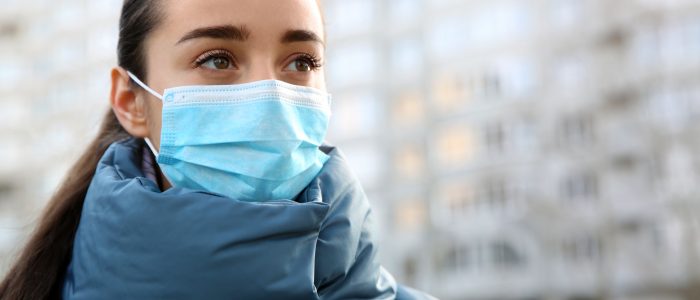 Woman wearing disposable mask outdoors. Dangerous virus