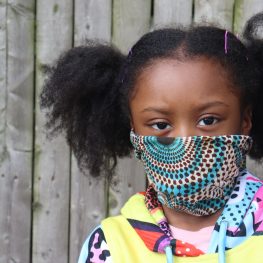 Girl Wearing Cloth Face Mask outside wooden fence background